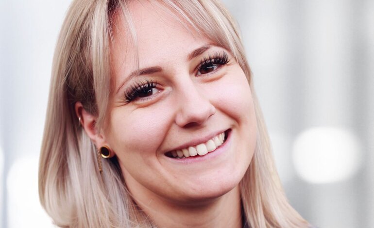 Das Bild zeigt eine lächelnde Frau, die direkt in die Kamera blickt. Sie hat blonde Haare, die in einem mittellangen Schnitt mit leichter Welle gestylt sind. | © privat