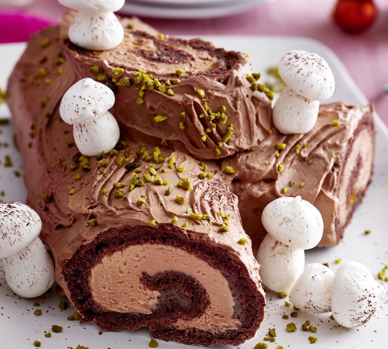 Weihnachtsbaum-Biskuitrolle auf einem weißen Teller auf rosa Hintergrund.  | © EAT CLUB / Isabell Triemer