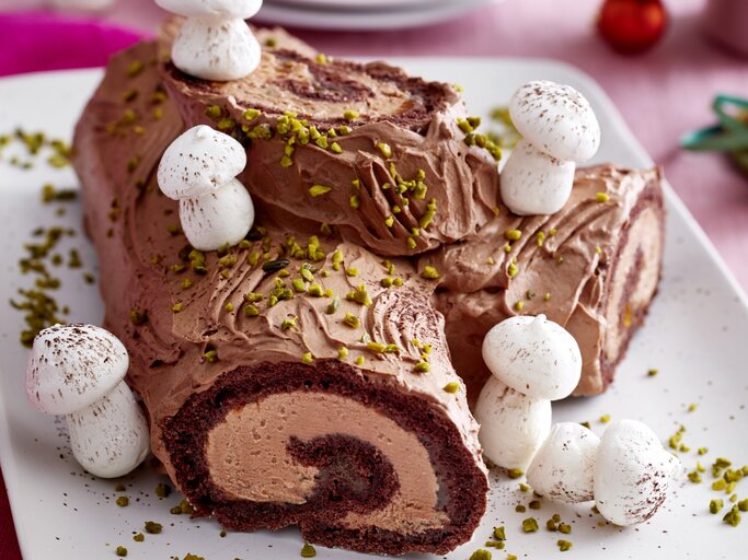 Weihnachtsbaum-Biskuitrolle auf einem weißen Teller auf rosa Hintergrund.  | © EAT CLUB / Isabell Triemer