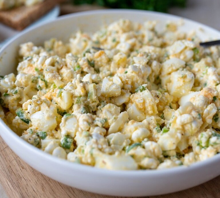Eiersalat ohne Mayonnaise in runder Porzellanschüssel / Untergrund Holzboden | © Adobe Stock / Angelika Heine