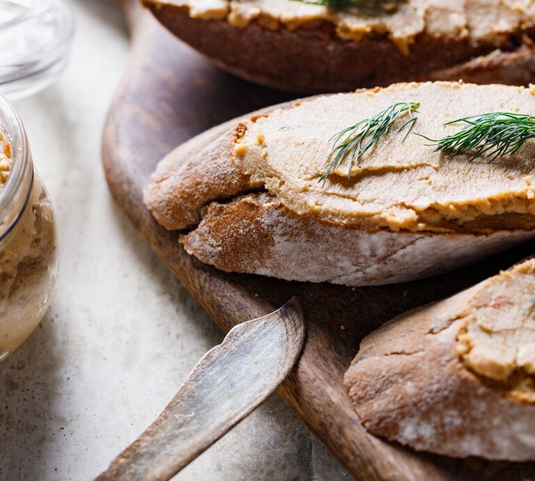 Thunfischcreme mit Dill auf zwei Weißbroten / Messer / Dip im Glas / Messer / Holzbrettchen | © Getty Images / Edalin