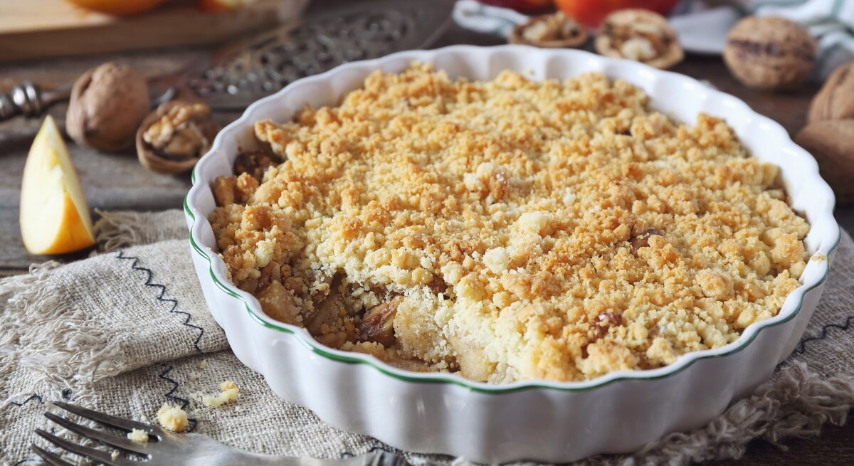Apfelkuchen mit Streusel und Walnüssen in runder Form / Apfelschnitten, frisch Walnüsse, Gabel
