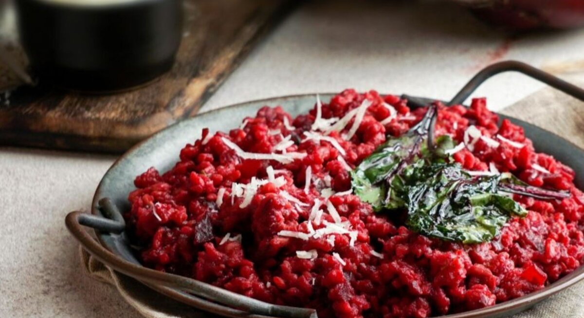 Teller mit vegetarischer One Pot Pasta in Tomaten- und Rote-Bete-Sauce, garniert mit Spinat und Käse.