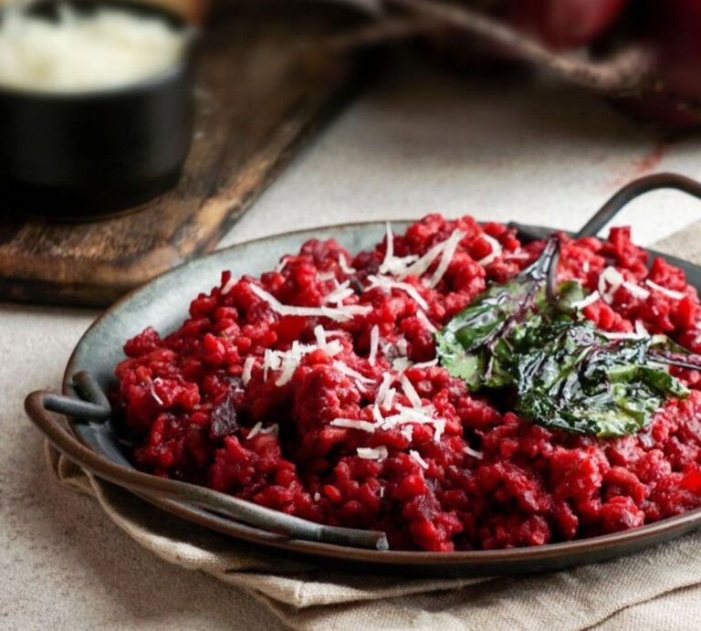 Teller mit vegetarischer One Pot Pasta in Tomaten- und Rote-Bete-Sauce, garniert mit Spinat und Käse. | © Getty Images / yulia-bogdanova