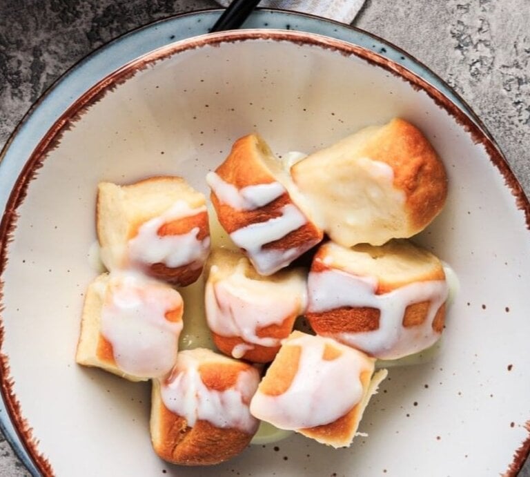 Vegane Buchteln mit Aprikosenmarmelade und Vanillesauce in einer Schüssel auf grauem Untergrund. | © Shutterstock / Ingrid Balabanova