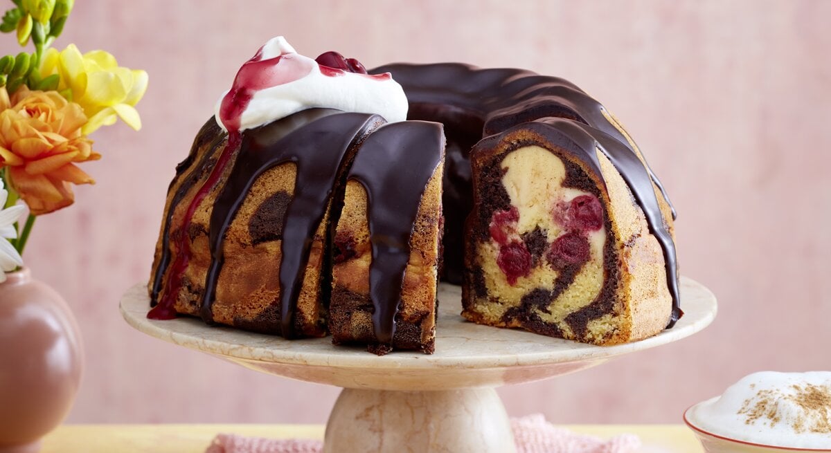 Der Gugelhupf auf einem Tortenständer mit rosa Hintergrund.