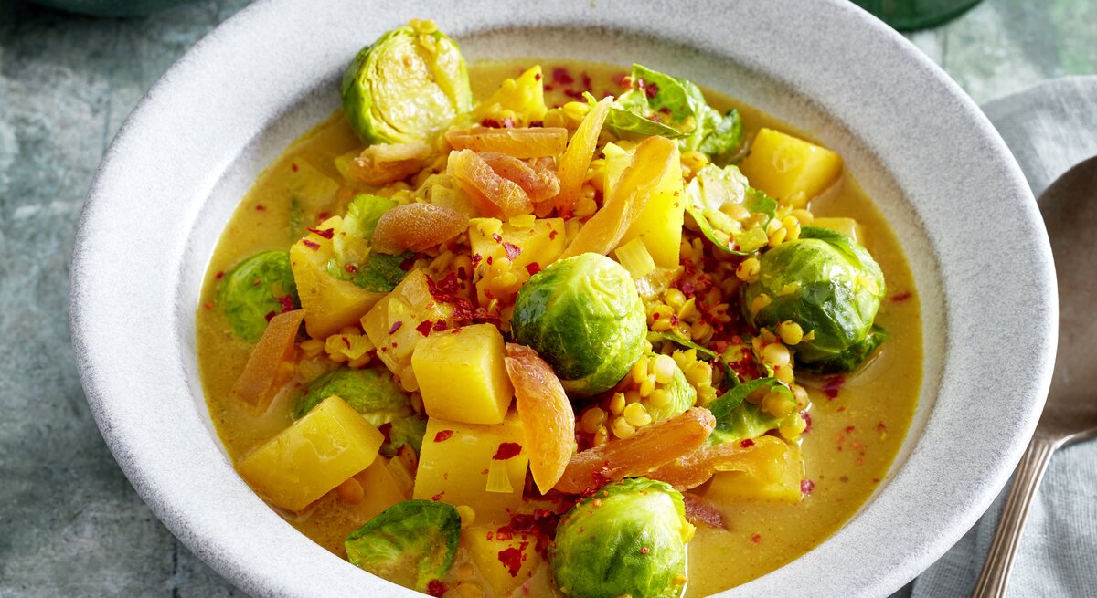 Rosenkohl-Steckrüben-Curry in einer weißen Schüssel auf grauem Hintergrund.