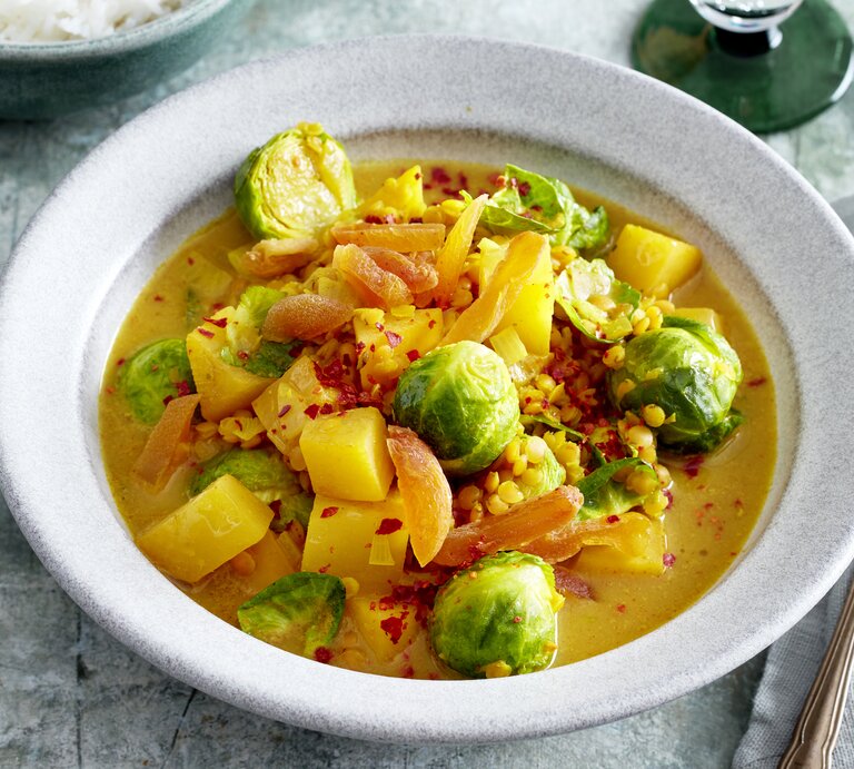 Rosenkohl-Steckrüben-Curry in einer weißen Schüssel auf grauem Hintergrund. | © EAT CLUB/Isabell Triemer