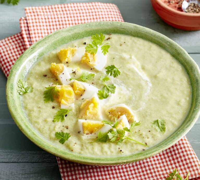 Eine Schale mit cremiger Lauch-Champignon-Suppe, verziert mit gehacktem hartgekochtem Ei und frischem Kerbel. Die Suppe hat eine hellgrüne Farbe mit weißen Joghurtwirbeln. | © EAT CLUB/Isabell Triemer