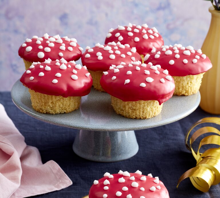 Frontalansicht von sechs Glückspilz-Muffins auf einer Etagere und einem auf einer vergoldeten Untertasse. | © EAT CLUB / Isabell Triemer