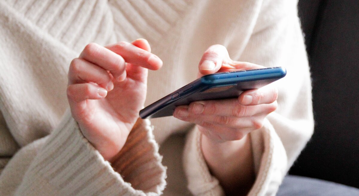 Zu sehen ist eine Frau, die ein Handy hält