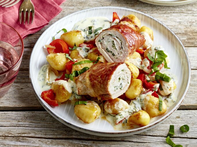 Bärlauch-Schnitzelröllchen auf einem weißen Teller auf hölzernem Hintergrund.  | © EAT CLUB/Isabell Triemer