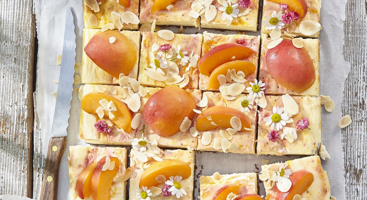 Aprikosen-Käsekuchen vom Blech auf weißem Backpapier auf hölzernem Hintergrund. 