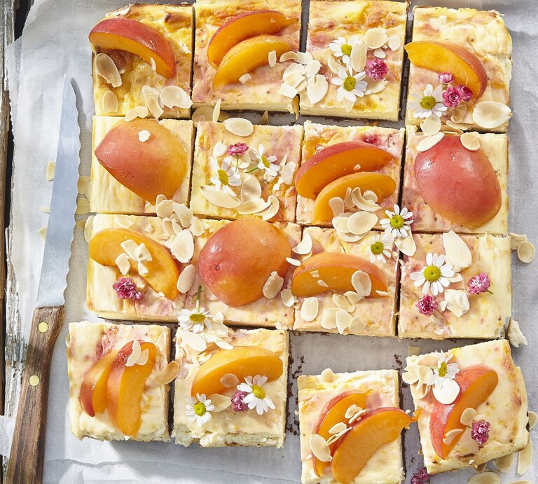 Aprikosen-Käsekuchen vom Blech auf weißem Backpapier auf hölzernem Hintergrund.  | © StockFood / Profimedia