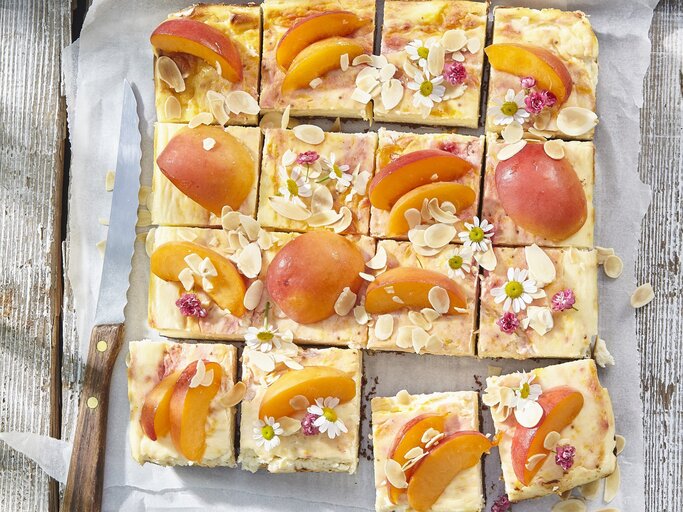 Aprikosen-Käsekuchen vom Blech auf weißem Backpapier auf hölzernem Hintergrund.  | © StockFood / Profimedia