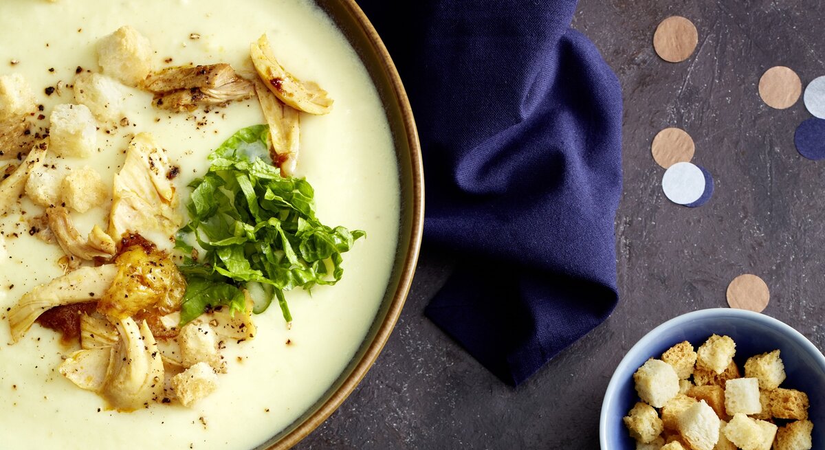 Draufsicht: eine Caesar-Suppe auf dunklem Untergrund.