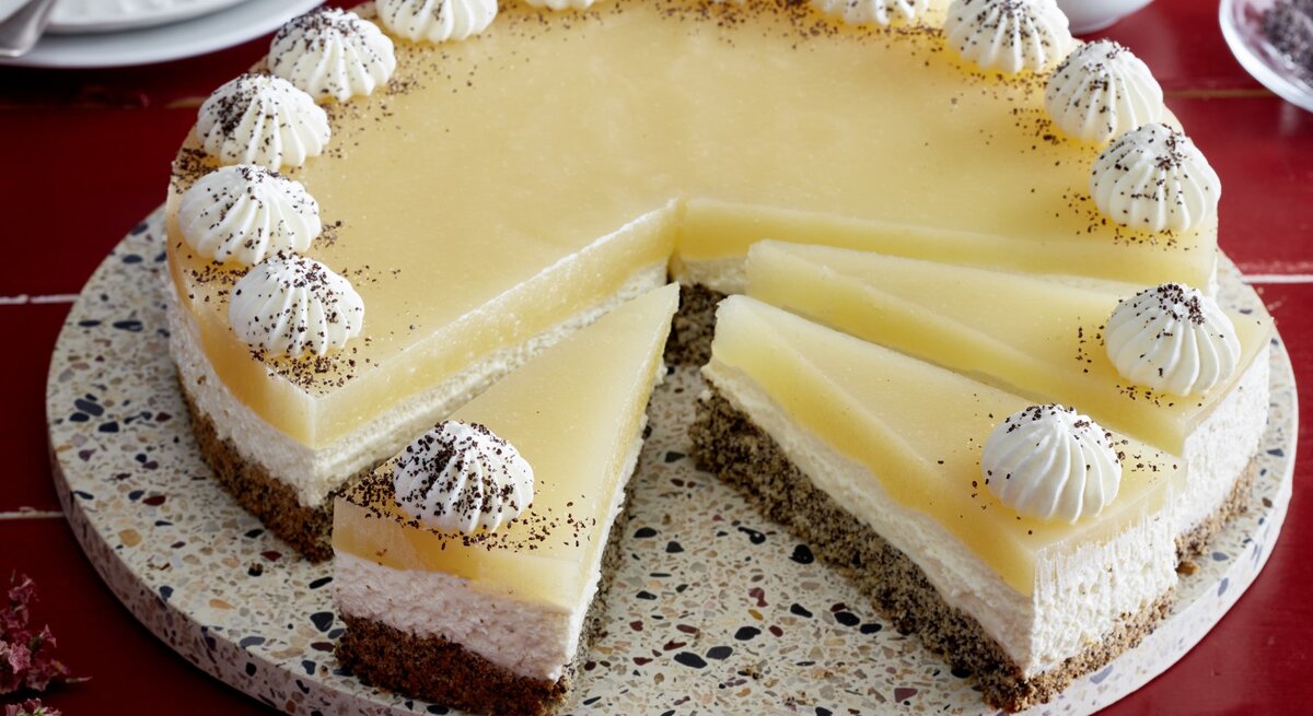 Birnen-Mohn-Torte auf einem Tortenteller auf rotem Hintergrund.