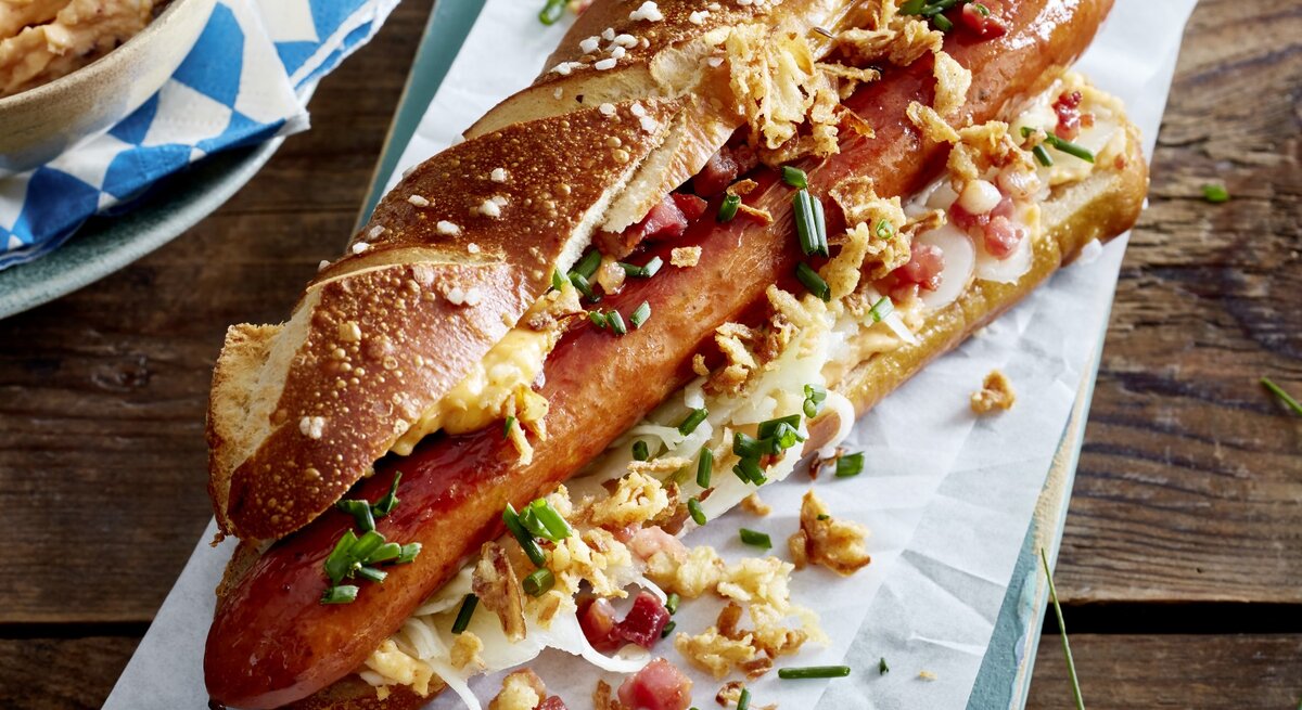 Hotdog auf bayerische Art auf weißem Papier auf hölzernem Hintergrund. 
