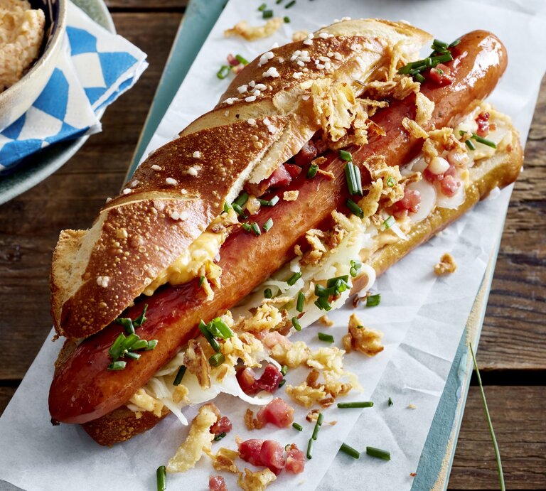 Hotdog auf bayerische Art auf weißem Papier auf hölzernem Hintergrund.  | © EAT CLUB/Isabell Triemer