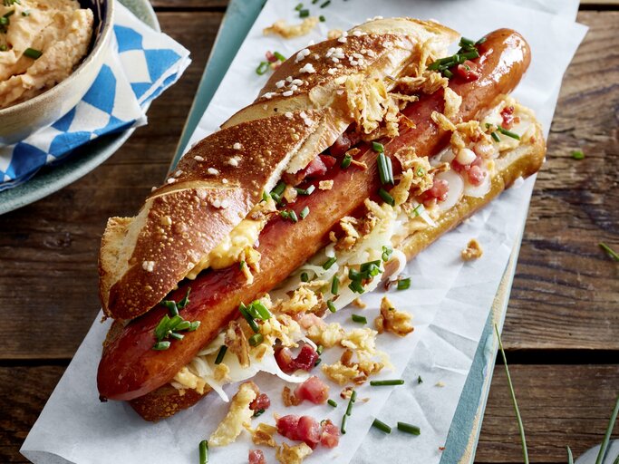 Hotdog auf bayerische Art auf weißem Papier auf hölzernem Hintergrund.  | © EAT CLUB/Isabell Triemer