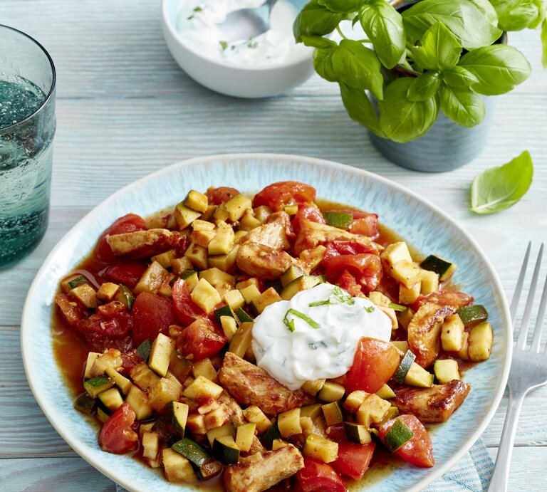 Steak-Streifen mit Tomaten-Zucchini-Ragout und frischem Kräuterquark angerichtet auf hellem Holz mit Basilikumdeko. | © EAT CLUB/Isabell Triemer