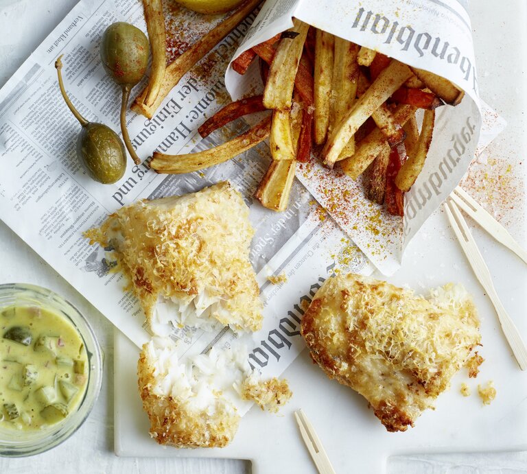 Rustikales Fish-and-Chips-Gericht mit Pommes in Papier, kross gebackenem Fisch, Zitronenspalten und Glas Remoulade. | © EAT CLUB/Isabell Triemer