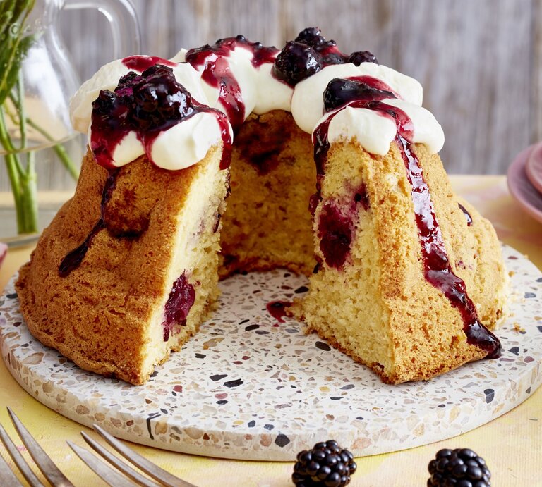 Brombeer-Apfel-Gugelhupf auf einem Tortenteller auf gelben Hintergrund.  | © EAT CLUB/Isabell Triemer