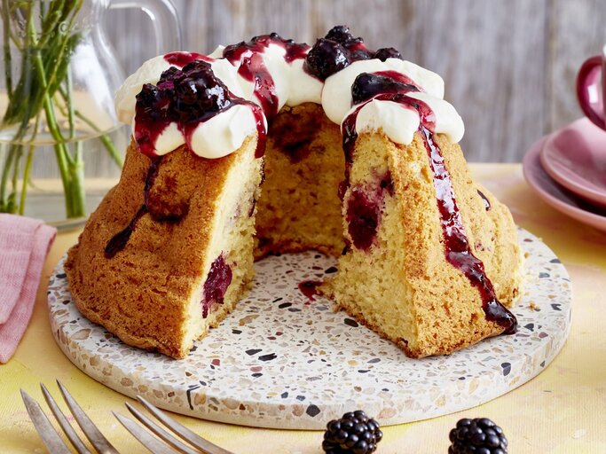 Brombeer-Apfel-Gugelhupf auf einem Tortenteller auf gelben Hintergrund.  | © EAT CLUB/Isabell Triemer