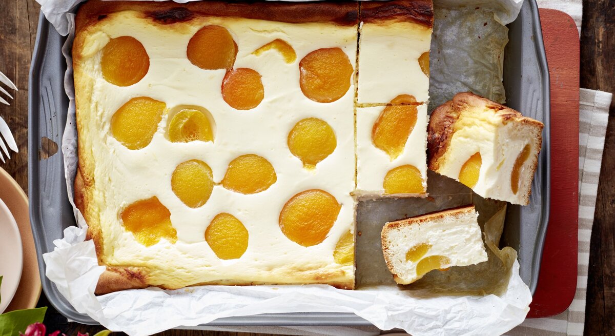 Aprikosen-Käsekuchen in einem Backblech auf hölzernem Hintergrund. 