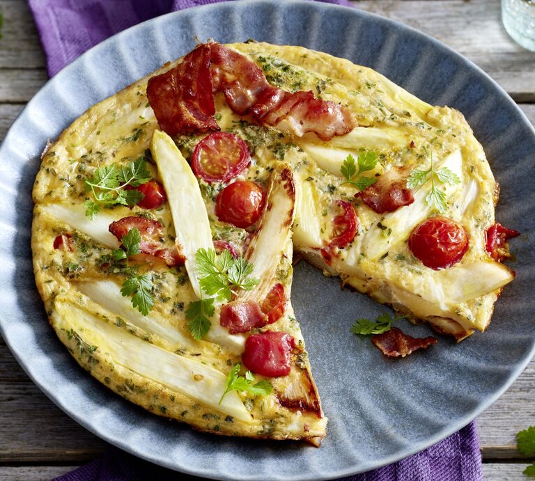 Spargel-Frittata auf einem blauen Teller auf hölzernem Hintergrund.  | © EAT CLUB/Isabell Triemer