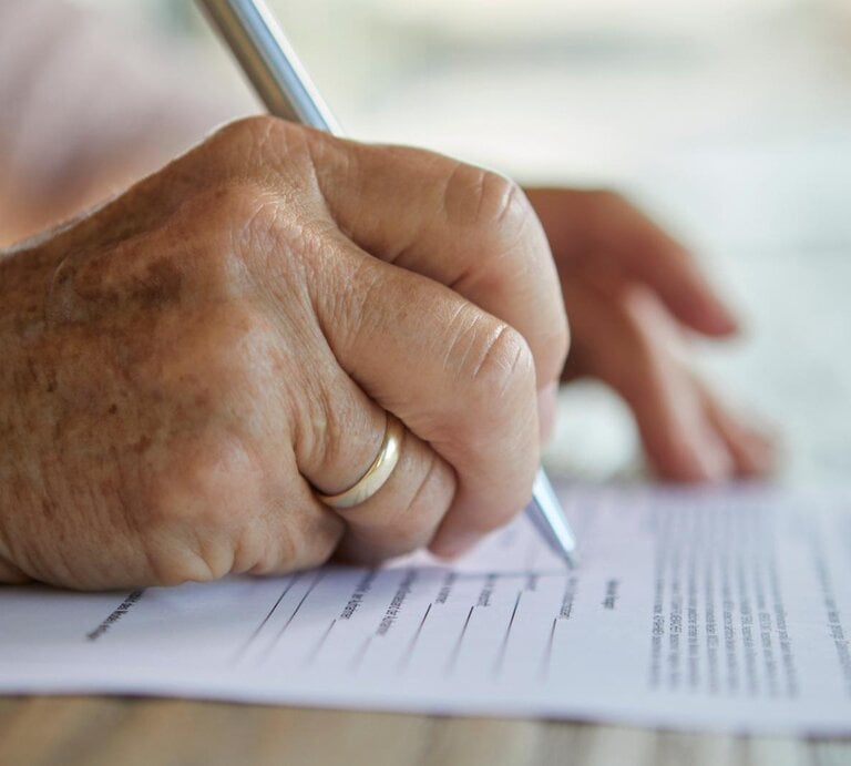 Nahaufnahme einer Hand einer älteren Dame, die mit einem Stift ein Formular ausfüllt.  | © Getty Images