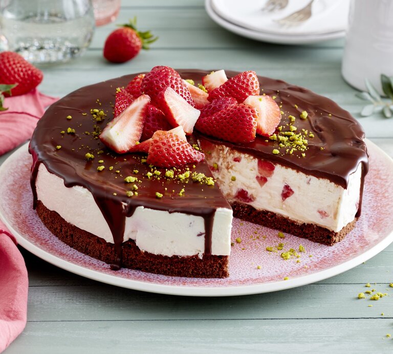 Joghurt-Erdbeer-Torte auf einem rosa Teller auf hellgrünem Hintergrund. Rechts Geschirr und links rosa Geschirrtuch.  | © EAT CLUB/Isabell Triemer