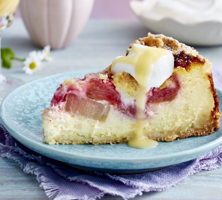 Rhabarber-Käsekuchen auf einem blauen Hintergrund. Hinten Gläser und Gänseblümchen verteilt. | © EAT CLUB/Isabell Triemer