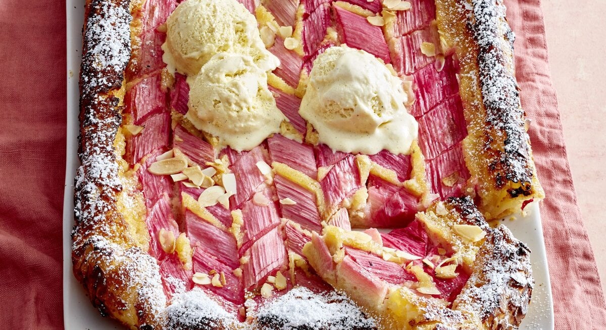 Rhabarber-Mandel-Galette auf einem weißen Teller auf rosa Hintergrund. 