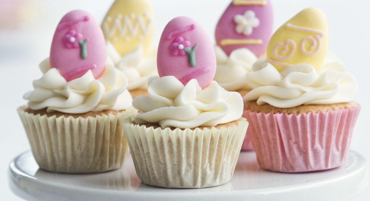 Oster-Cupcakes mit Windbeuteln auf einem weißen Servierteller.