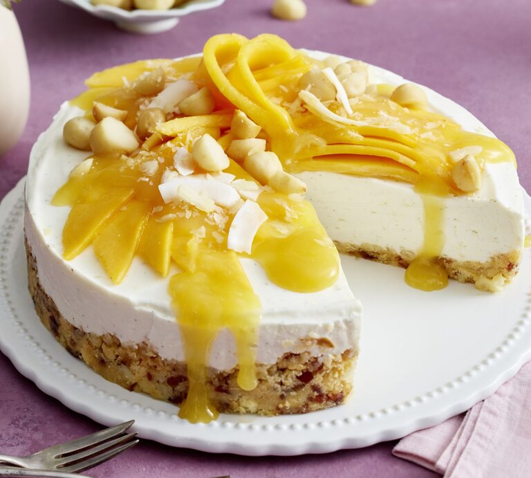 Macadamia-Kokos-Cheesecake auf einem Tortenteller auf rosa Hintergrund. | © EAT CLUB/Isabell Triemer
