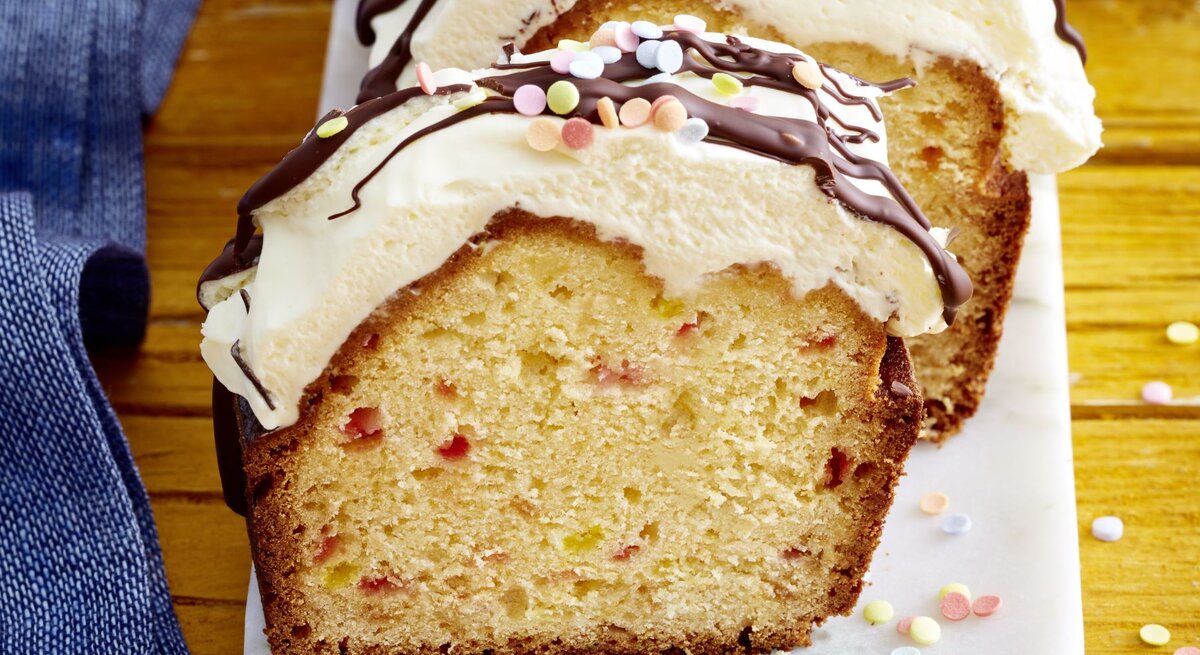 Funfetti-Kuchen mit Schwips auf einem weißen Teller auf hölzernem Hintergrund. 