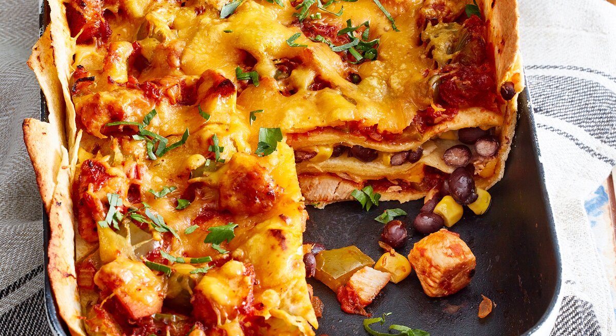 Tortilla-Hähnchen-Lasagne in einer Auflaufform auf einem Geschirrtuch.