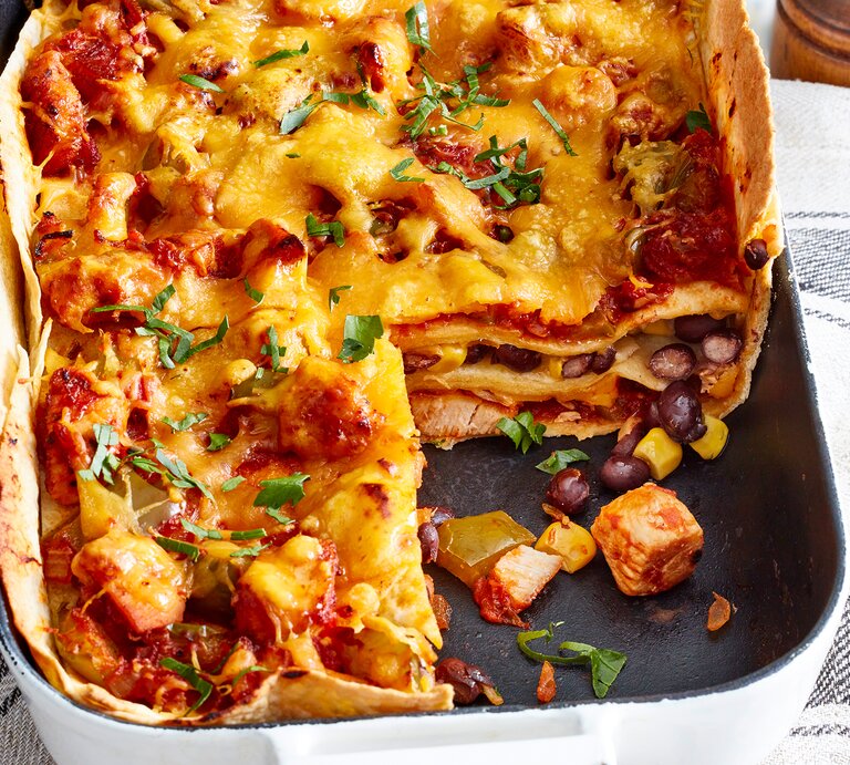 Tortilla-Hähnchen-Lasagne in einer Auflaufform auf einem Geschirrtuch. | © EAT CLUB/Isabell Triemer