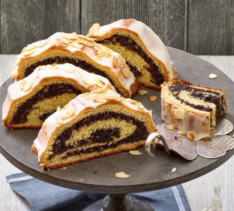 Mohnstollen auf einem schwarzen Tortenteller auf hölzernem Hintergrund.  | © EAT CLUB / Matthias Liebich
