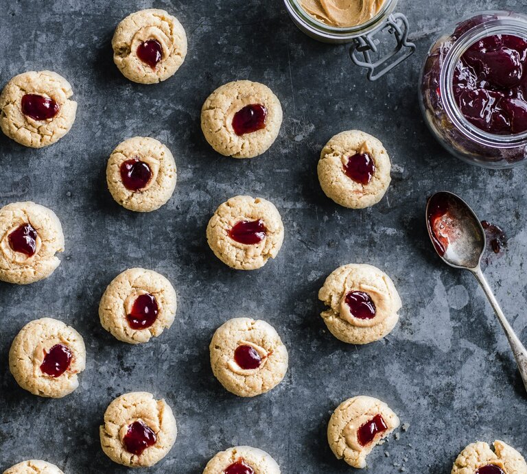 Kekse mit Marmelade und Erdnussbutter auf grauem Hintergrund, rechts ein Glas gefüllt mit Marmelade. | © StockFood / Immediate Media / Olive#