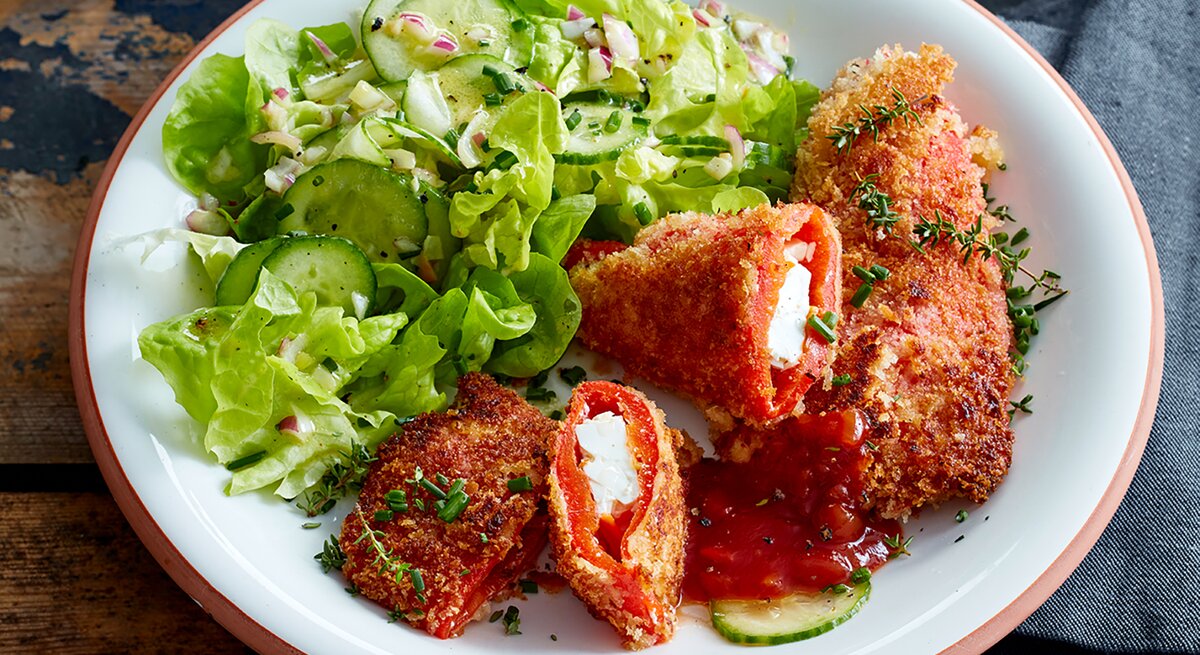 Feta-Paprika-Cordon-bleu auf einem weißen Teller auf hölzernem Hintergrund.