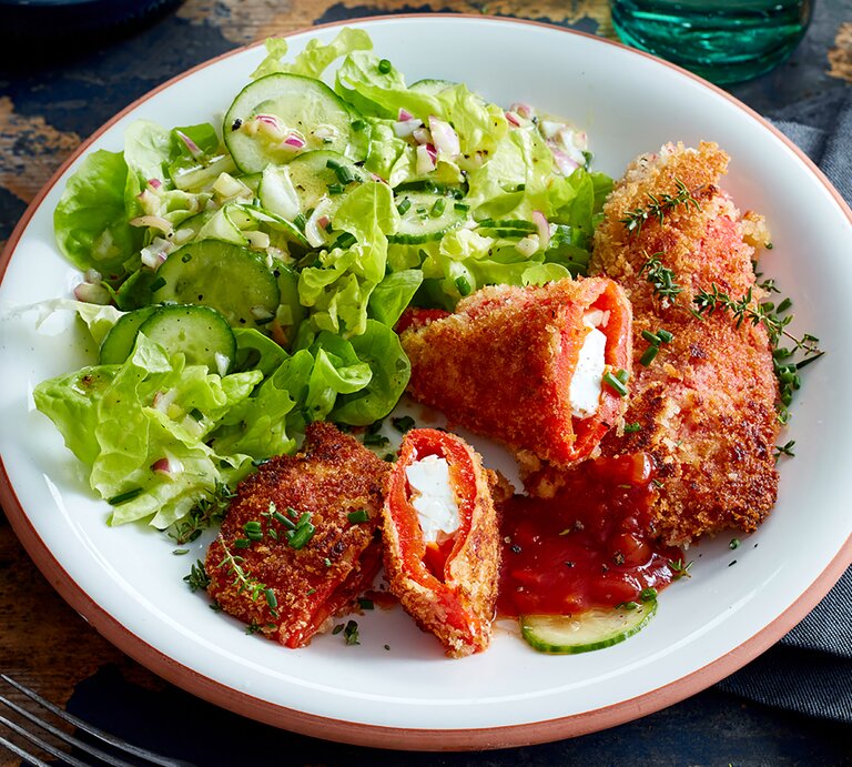 Feta-Paprika-Cordon-bleu auf einem weißen Teller auf hölzernem Hintergrund. | © EAT CLUB/Isabell Triemer
