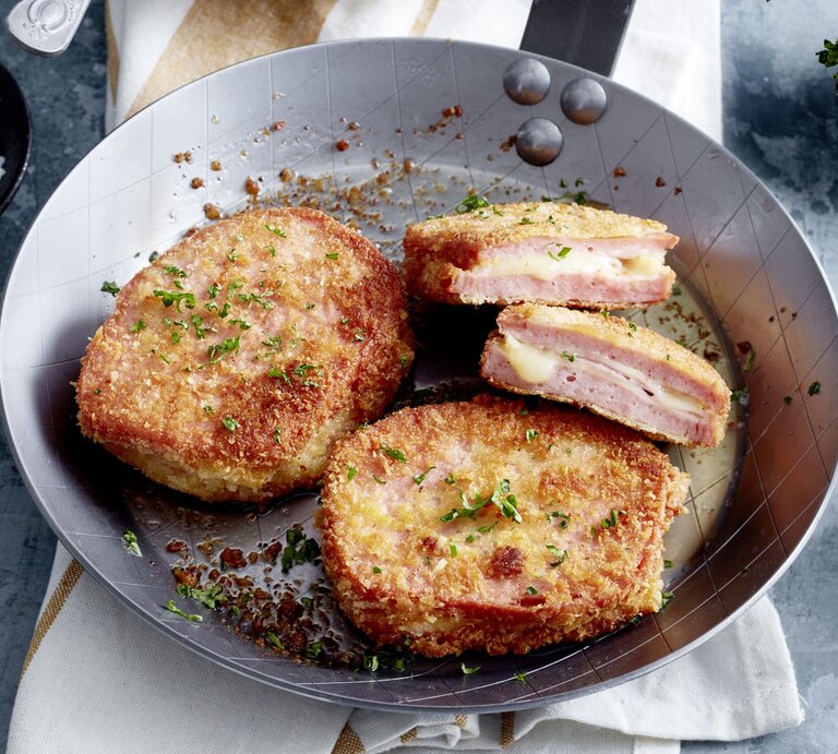 Fleischkäse-Cordon-bleu in einer Pfanne auf einem weißen Tuch auf silbernem Hintergrund. | © EAT CLUB/Isabell Triemer