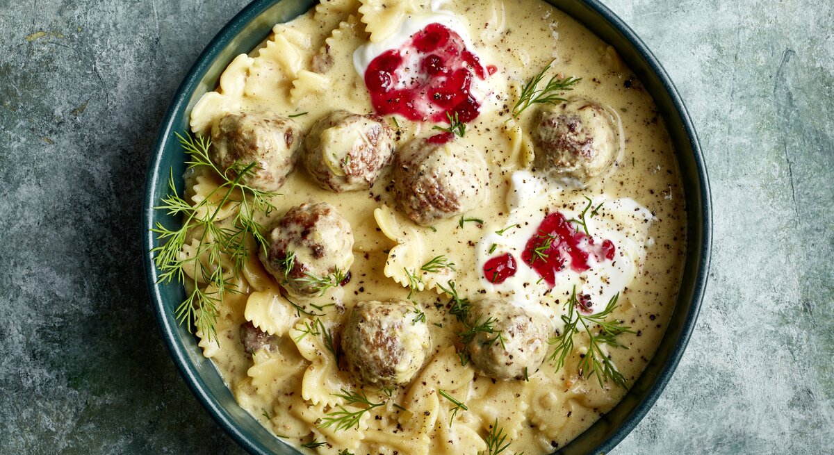 One-Pot-Pasta Köttbullarstyle in einer dunkelblauen Schüssel auf grauem Hintergrund.