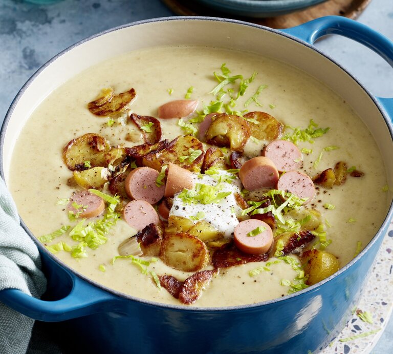 Bratkartoffel-Suppe mit Würstchen in einem blauen Topf auf grauem Hintergrund.  | © EAT CLUB/Isabell Triemer
