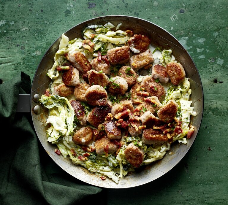 Gnocchi „Amore mio“ auf cremigen Wirsingstreifen in einer schwarzen Pfanne auf dunkelgrünem Hintergrund. | © EAT CLUB/Isabell Triemer