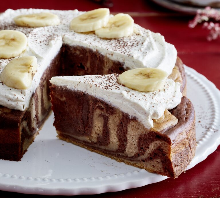 Zebra-Bananen-Kuchen angeschnitten auf einem weißen Teller auf rotem Hintergrund. | © EAT CLUB/Isabell Triemer