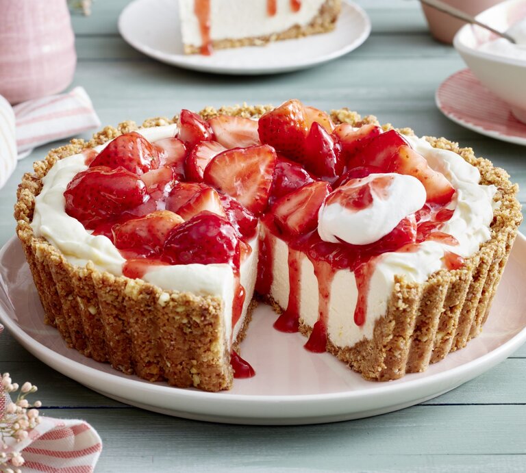 Erdbeer-Zitronen-Pie auf einem rosa Servierteller auf hellgrünem Hintergrund. Auf dem Foto hinten rosa Geschirr verteilt. | © EAT CLUB/Isabell Triemer