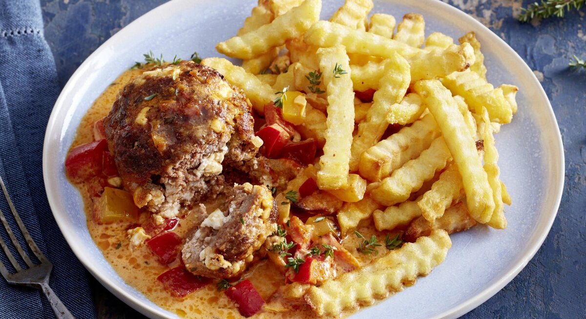 Mini-Braten in Paprika-Rahm auf einem weißen Teller auf dunkelblauem Hintergrund.